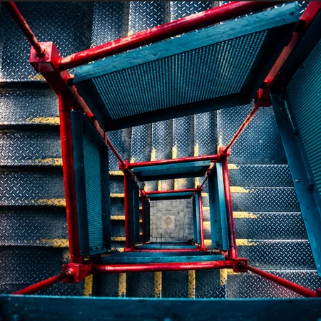 Looking straight down a red-railed iron spiral stairwell in Castlefield, Manchester
