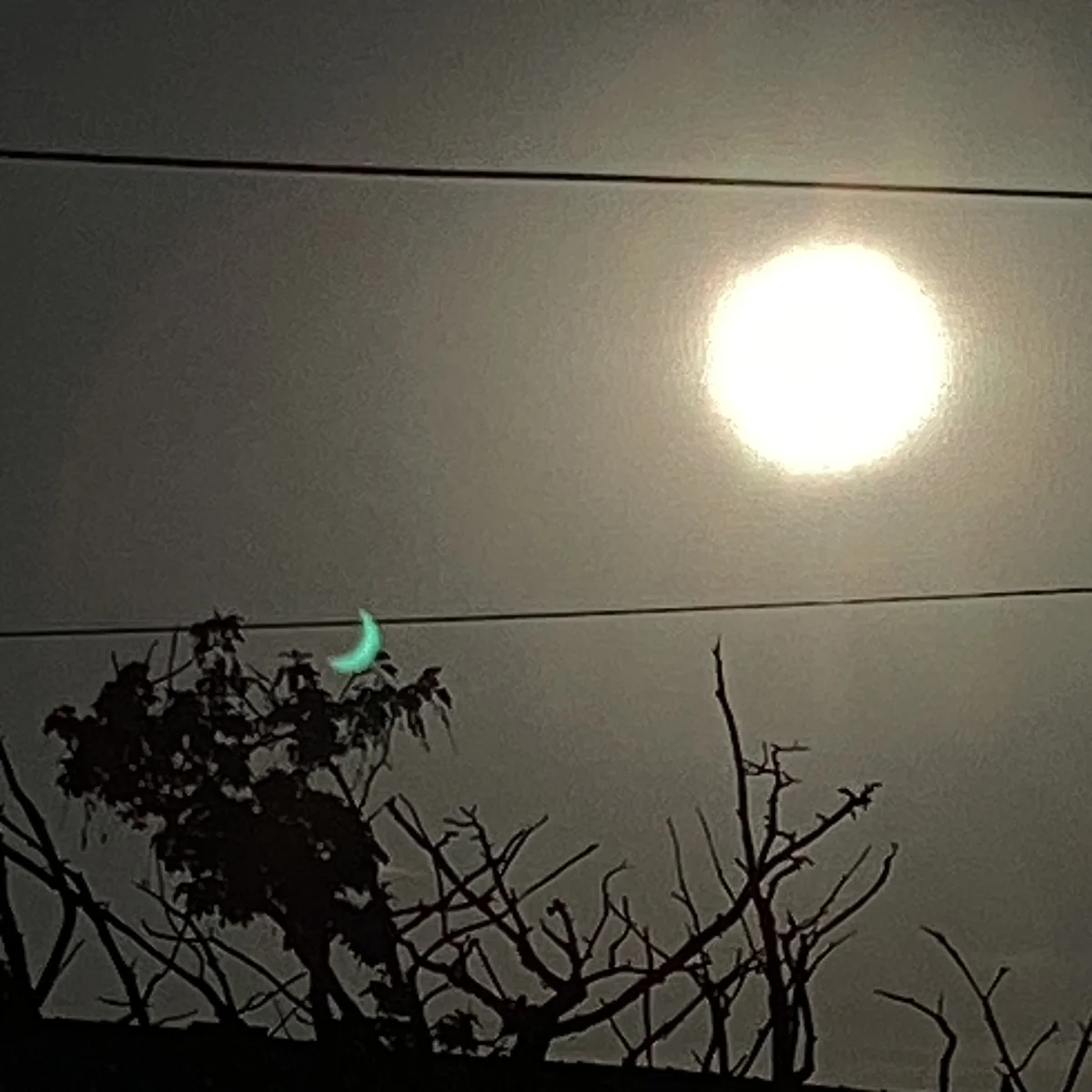 Photograph taken at 18:56 BST on 12 August 2026 from Tottington, Bury, Greater Manchester (53.6143N, 2.3393W) during the 2026 partial solar eclipse. The image shows a full, unobstructed circular solar disk with no lunar occultation visible. A small cyan crescent feature is visible, identified as lens flare by AI image analysis. EXIF metadata confirms the time, date and GPS location.