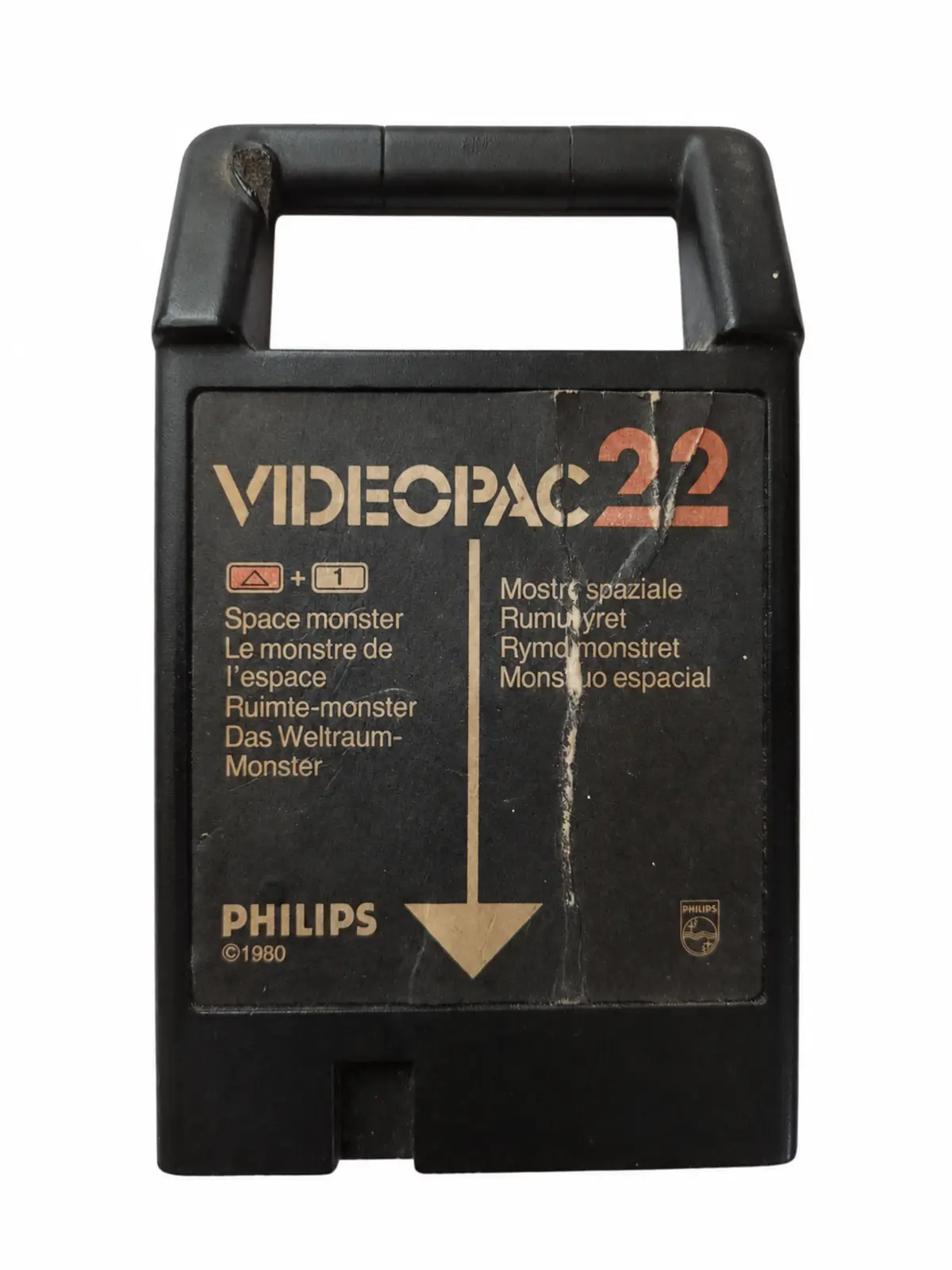 The original Videopac 22 Space Monster cartridge by Philips, copyright 1980, showing the worn label with multilingual title and a soldering iron scar on the handle