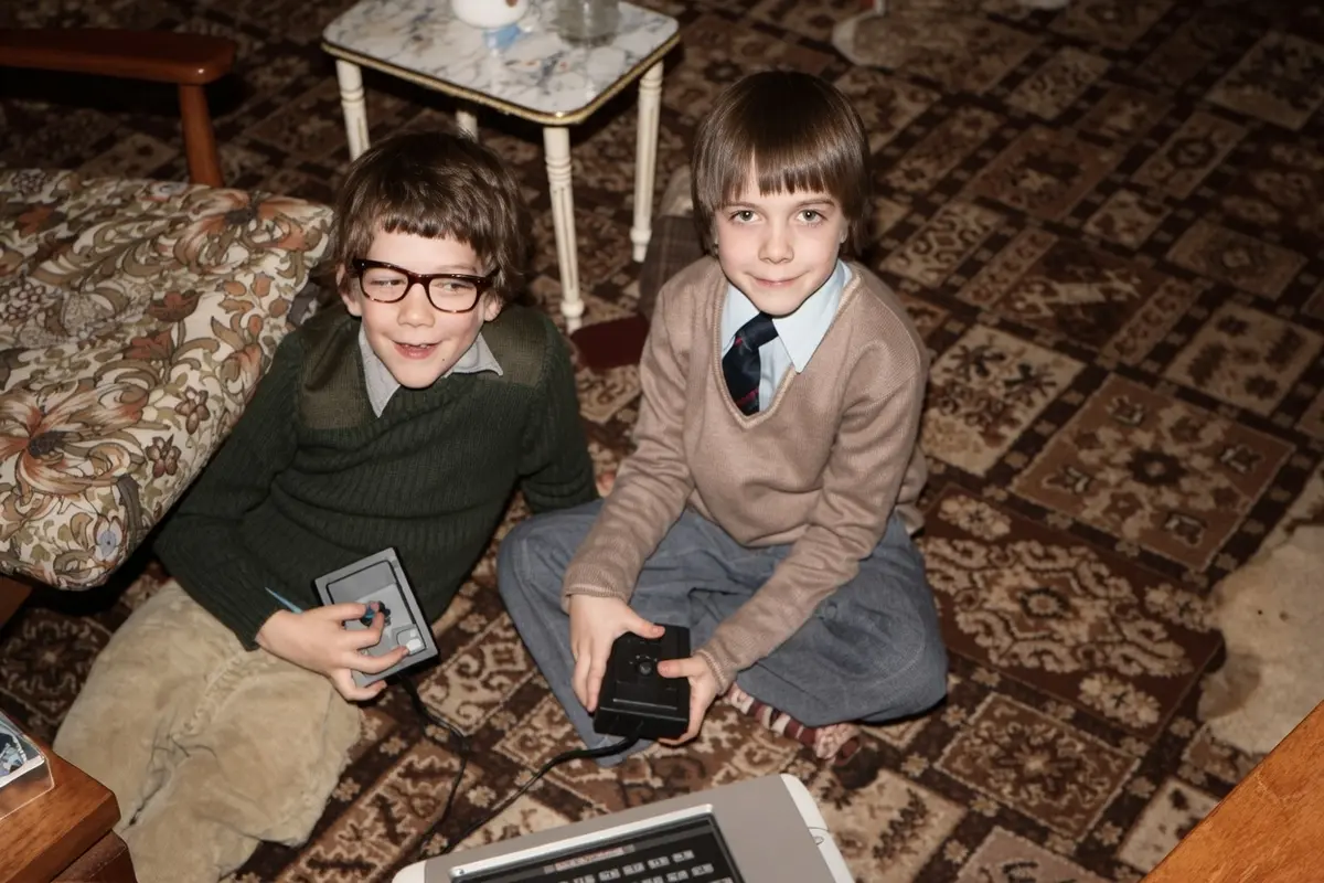 Two young brothers sitting on the living room floor on Christmas Day 1982, each holding a Philips Videopac G7000 controller, with the console visible at the bottom of the frame